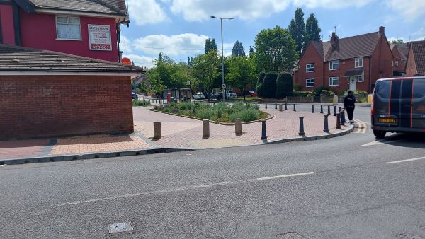 Image of a wide paved plaza outside a row of shops incorporating a rain garden