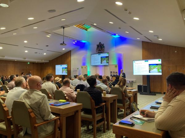Image of a room full of delegates, with a speaker at the front